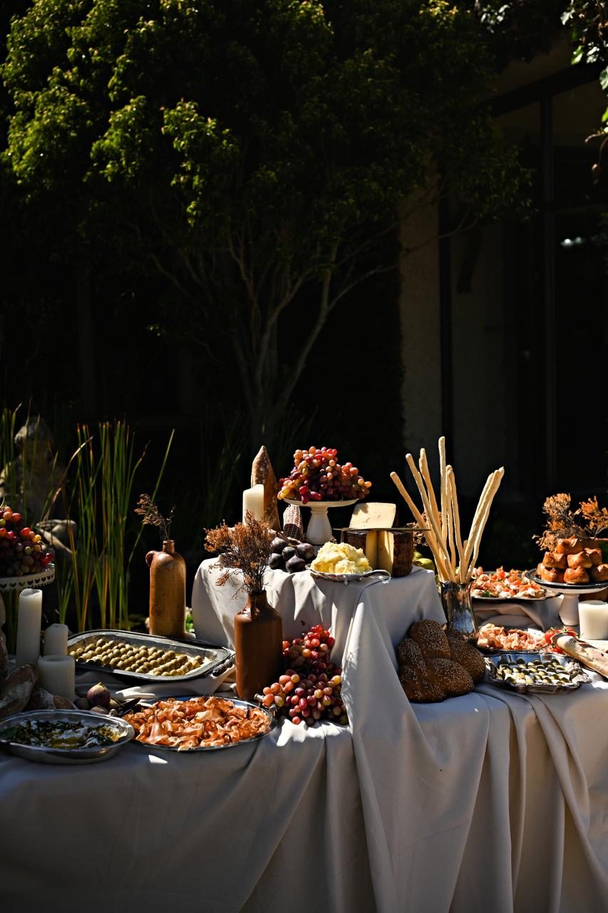 A decadent harvest table of canapés, cheeses, breads and grapes