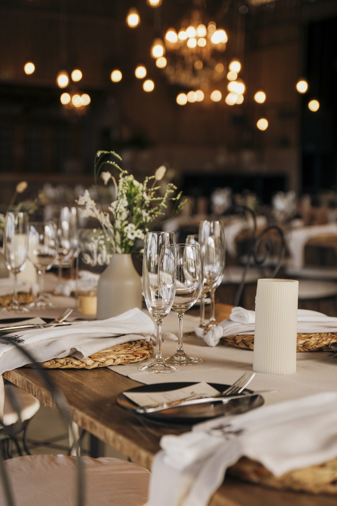 A long table set with candles and glassware beneath the chandeliers