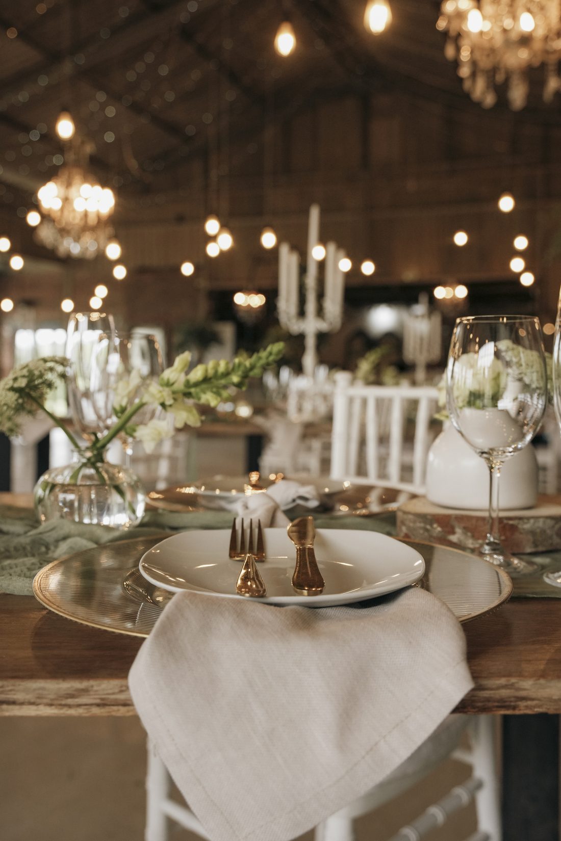 A place setting with gold cutlery and candlelight in the barn