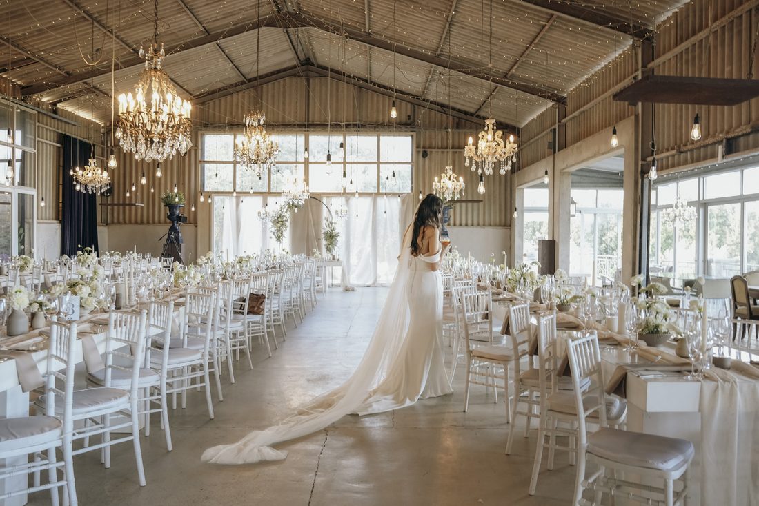 The barn set for a reception, long tables beneath the chandeliers