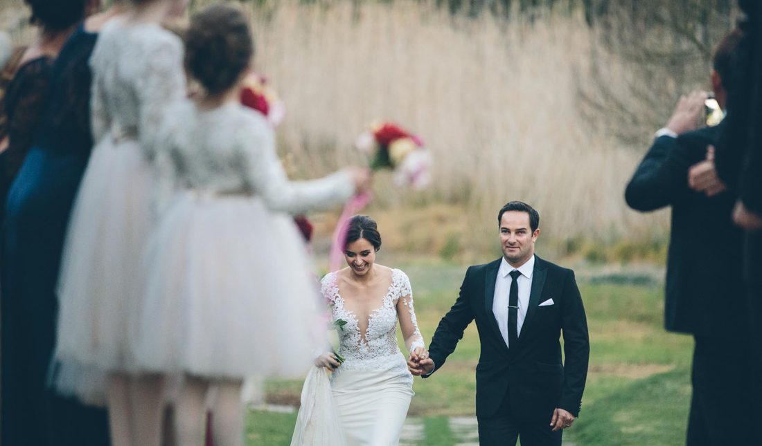 A couple walking back down the aisle past their guests on the farm