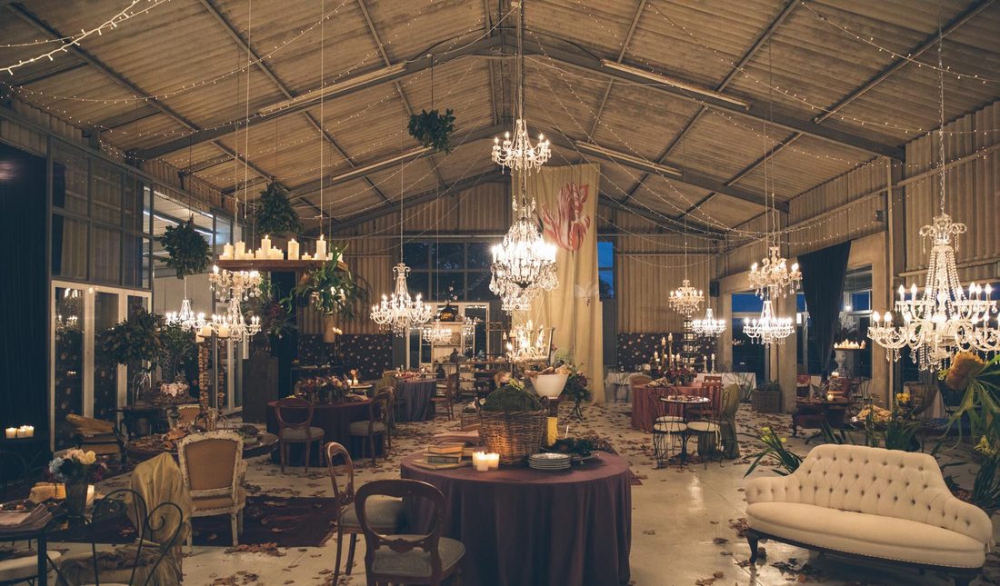 The barn at dusk, chandeliers and candlelight over tables set for a celebration