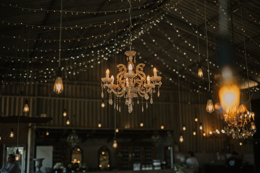 A chandelier and strings of lights across the barn roof
