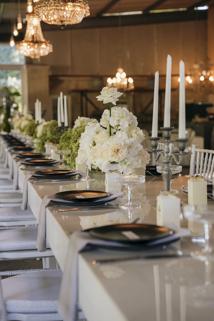 A long table laid with candles and hydrangeas